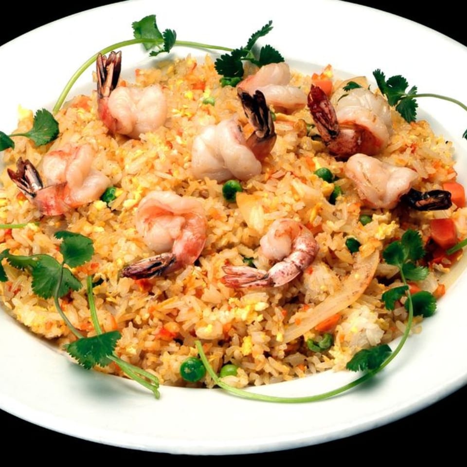 Shrimp fried rice with peas, carrots, and cilantro on a white plate.