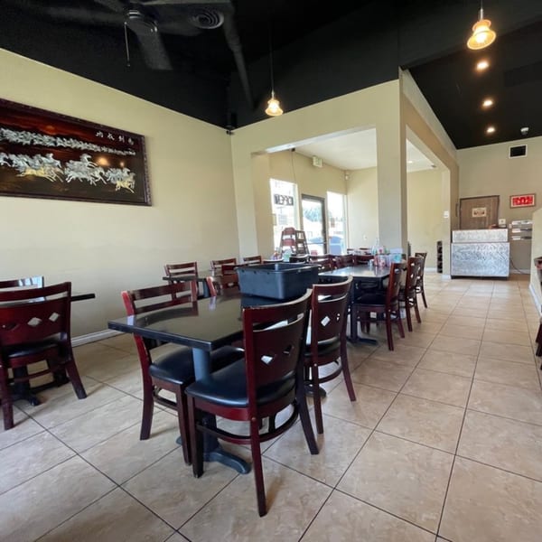 Interior of Pho Super Bowl, showing empty dining tables and chairs with light-colored walls and dark ceiling.